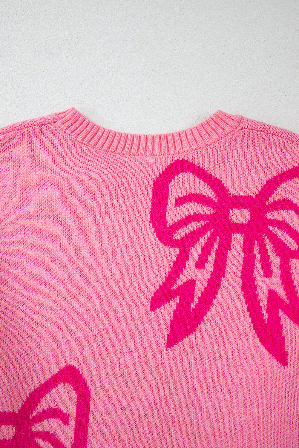 Maglione largo con spalla cadente e motivo fiocco rosa